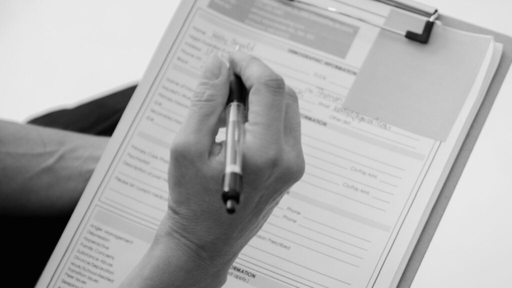 photo of a checklist with a persons hand holding a pen poised to fill it out